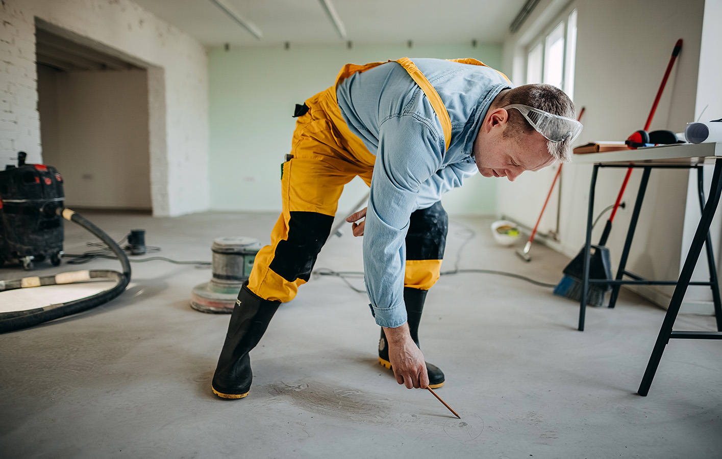 Verkleben von Parkettboden sollte von Profis übernommen werden. Bauarbeiter markiert auf Baustelle die Begrenzungen