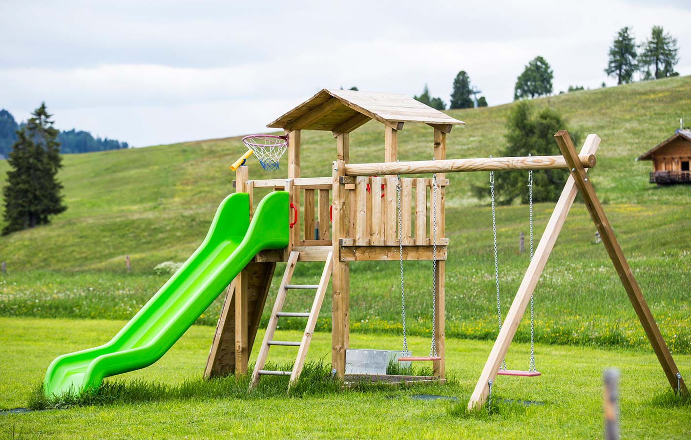Kinderspieltürme mit Rutsche und Schaukel für den Garten Ein Spielturm aus Holz mit Rutsche und Schaukel auf einer Wiese