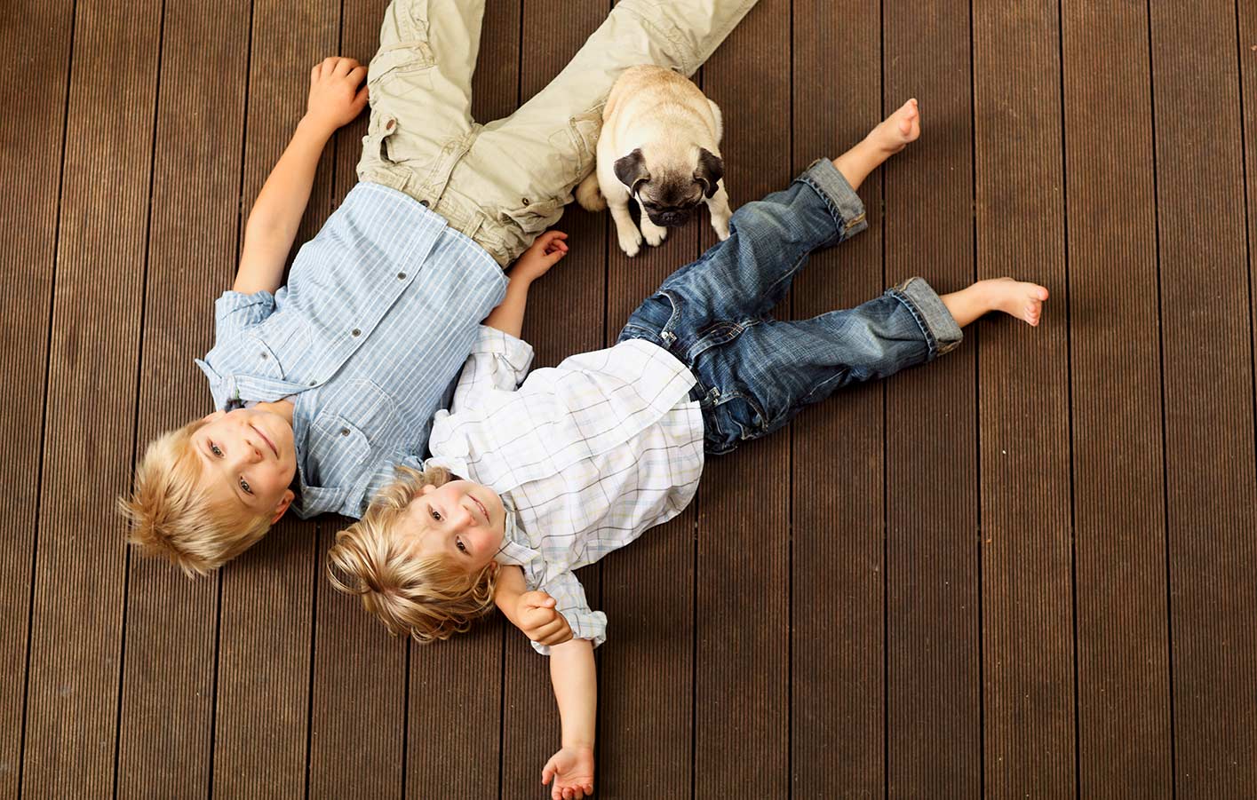 Tropenholz als Terrassendielen - wie sieht es mit dem Naturschutz aus Kinder liegen auf einer Terrasse aus Holz